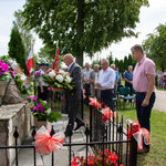 Grupa ludzi składająca kwiaty przy pomniku